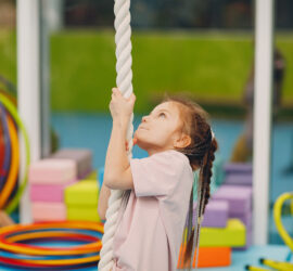 Ein Kind klettert im Kinderturnen ein Seil hoch